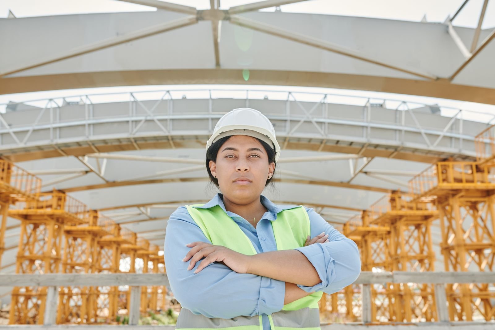 Carpenter in a hard hat standing among glue-laminated timber beams