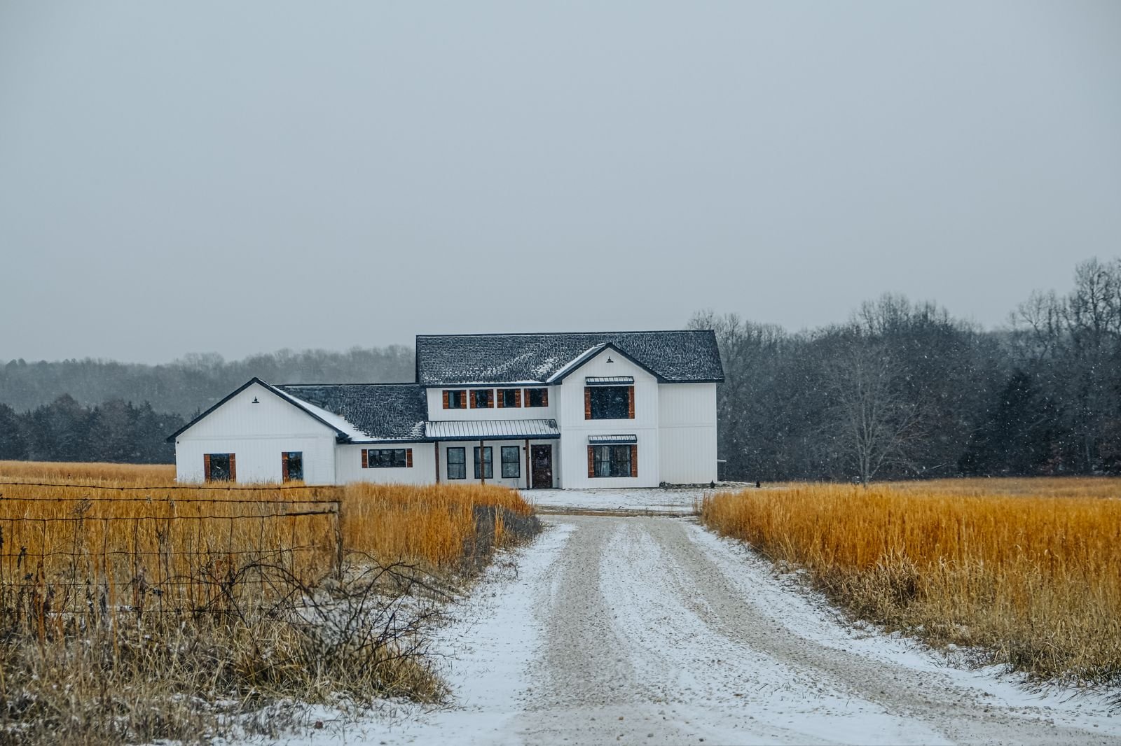 House and outbuilding across an open winter field