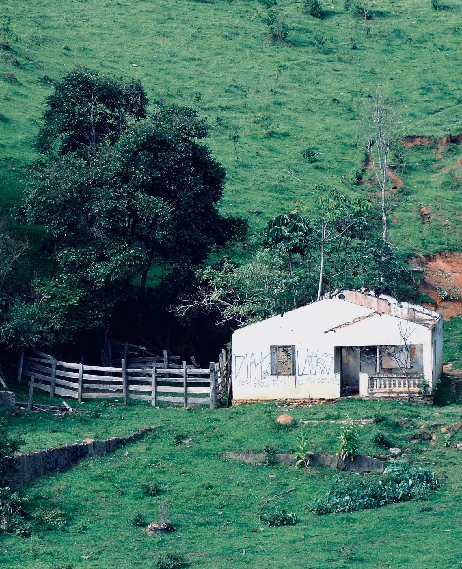 Small white outbuilding on open ground with mountains beyond