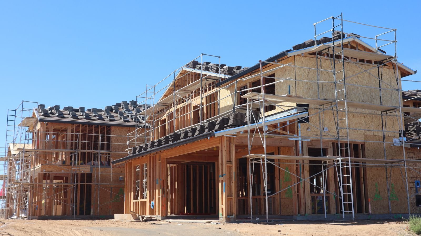 Heavy timber frame structure under construction against a mountain backdrop