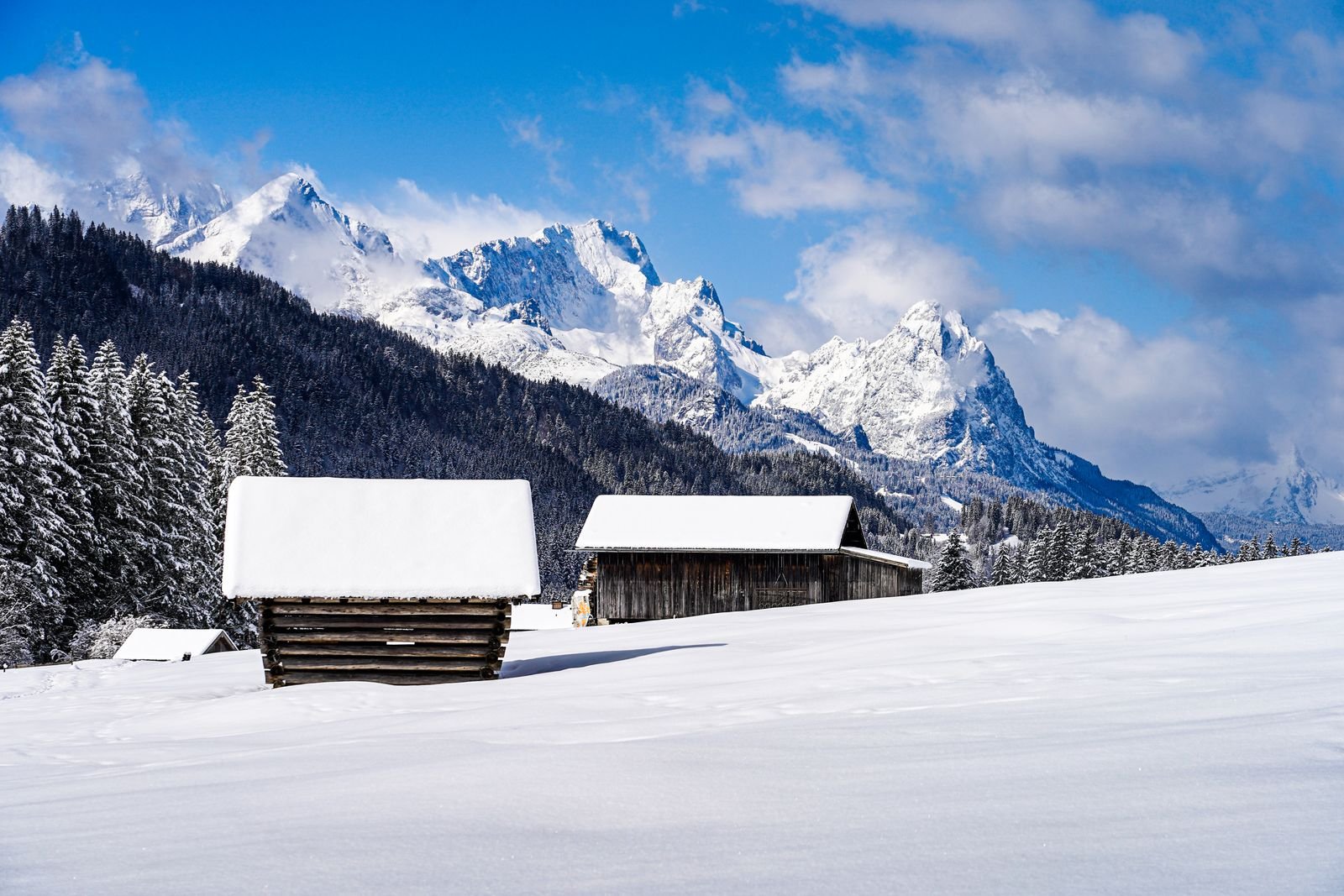 Snow-covered outbuilding with mountains behind it in winter